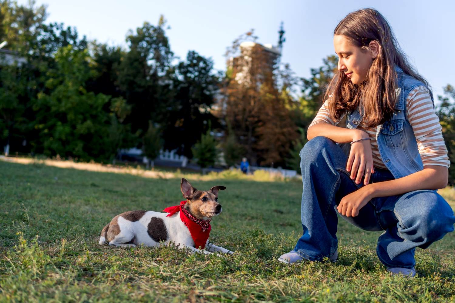 Owner sitting beside her calm, attentive dog at the park during a real-world training session